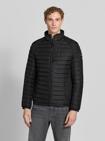 Männermodel trägt Regular Fit Jacke in Stepp-Optik Modell 'OLYMPUS' von NAUTGÅRD in Schwarz, glatte Struktur, Ganzkörperansicht von vorne. Kontext: Stehkragen, Reißverschluss, Rückenlänge 69 cm, Schulterbreite 48 cm, Brustweite 48 cm, Ärmellänge 67 cm.