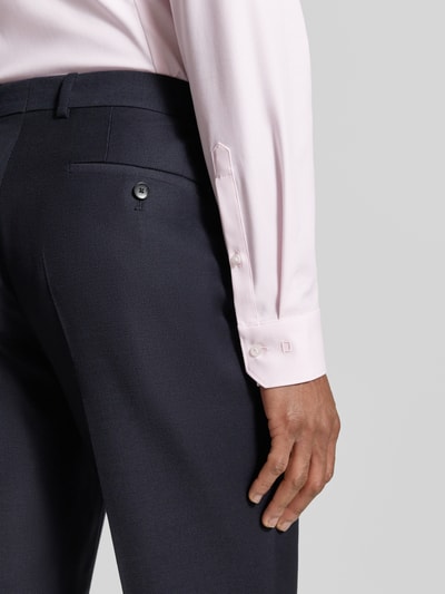 Männermodel trägt Super Slim Fit Business-Hemd Modern Kent Uni Twill von OLYMP No. Six in Hellrosa, Details des elastischen Baumwoll-Mix, Nahaufnahme Oberkörper seitlich.