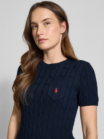Frauenmodel trägt Slim Fit Kurzarmpullover mit Label-Stitching von Polo Ralph Lauren in Dunkelblau, reine Baumwolle, Strick-Optik, Rundhalsausschnitt, Brusttasche mit rotem Logo-Stitching, elastische Abschlüsse, Nahaufnahme Oberkörper.