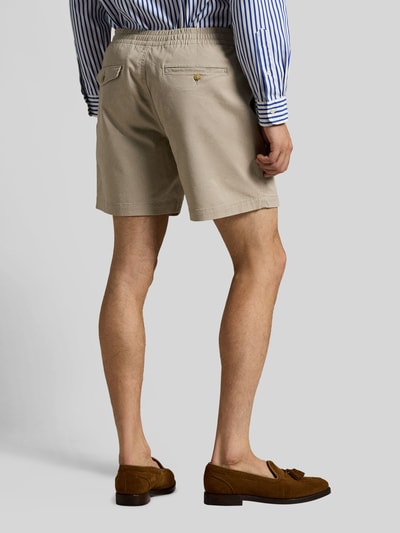 Mężczyzna nosi Regular Fit Shorts aus Baumwoll-Mix od Polo Ralph Lauren, jednolity beżowy kolor, elastyczny dół nogawek, widok z tyłu, zdjęcie całej sylwetki.