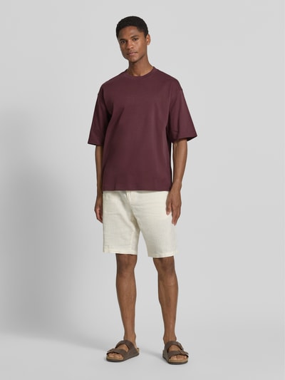 Männermodel trägt Relaxed Fit T-Shirt mit Rundhalsausschnitt von JAKE*S STUDIO MEN aus reiner Baumwolle, Kurzärmelig, Farbe Bordeaux, kombiniert mit heller Shorts, Ganzkörperansicht von vorne. Rückenlänge bei Größe M: 67 cm.