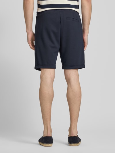 Männermodel trägt Sweatshorts mit elastischem Bund und Gesäßtasche von MCNEAL in Dunkelblau, feine Struktur, Ganzkörperansicht Rückansicht, Regular Fit, Viskose-Mix, Tunnelzug, Größe M: Bundweite 44 cm, Innenbeinlänge 21 cm.