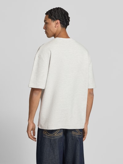 Männermodel trägt Oversized T-Shirt mit Strukturmuster und Label-Stitching von Pegador aus reiner Baumwolle, Rückenansicht Ganzkörperansicht.