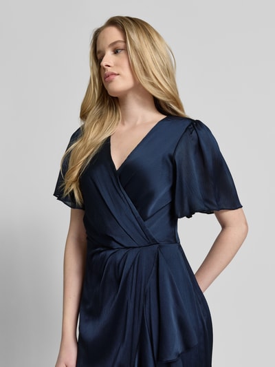 Frauenmodel trägt Cocktailkleid in Wickel-Optik mit V-Ausschnitt von Lipsy, dunkelblauer Satin, taillierter Schnitt, Nahaufnahme Oberkörper.