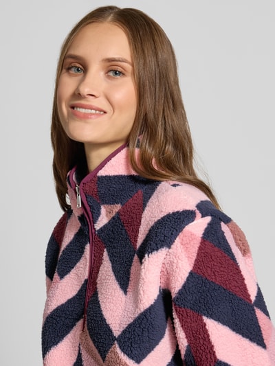 Kobiece modelka nosi Regular Fit Troyer mit Stehkragen Modell 'NEW' od ONLY o geometrycznym wzorze w odcieniach różu i granatu, tekstura miękkiego polaru, zbliżenie na górną część ciała, damski troyer od ONLY.