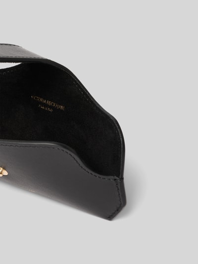 Produktfoto, Sonnenbrillenetui aus Leder von Victoria Beckham in Schwarz mit Überschlag, Label-Detail, Tragehenkel und Hauptfach, glatte Textur.