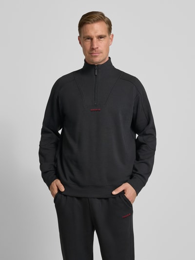 Męski model nosi Regular Fit Sweatshirt aus Baumwoll-Mix Modell 'ATLAS' von HUGO, jednokolorowy, nadruk z logo, troyer, długi rękaw, mieszanka bawełny, dzianina dresowa, Ganzkörperansicht von vorne.