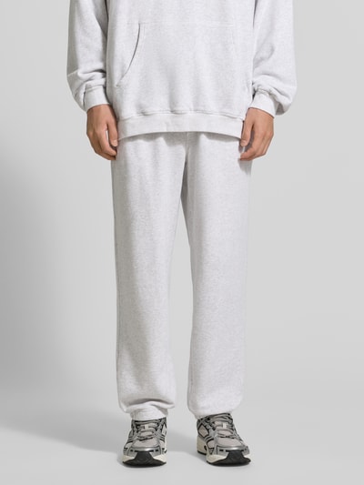 Männermodel trägt Sweatpants mit Eingrifftaschen Modell 'ATUBAY' von American Vintage, Baumwoll-Elasthan-Mix, Relaxed-Fit, elastischer Bund, Tunnelzug, hellgraue Farbe, glatte Textur, Ganzkörperansicht von vorne.