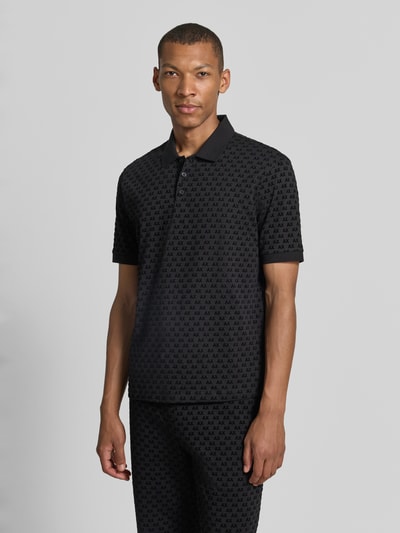Männermodel trägt Regular Fit Poloshirt aus reiner Baumwolle von Armani Exchange mit Allover-Logo-Print, dezentes Schwarz, Ganzkörperansicht von vorne.