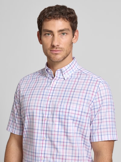 Męski model nosi Regular Fit Business-Hemd mit Button-Down-Kragen von OLYMP z bawełny, w kratę, rękaw o dł. 1/2, długość tyłu 80 cm, szerokość ramion 45 cm, długość rękawów 28 cm, kolor biały z niebieskimi i różowymi liniami, tekstura gładka, widok na górną część ciała z przodu.