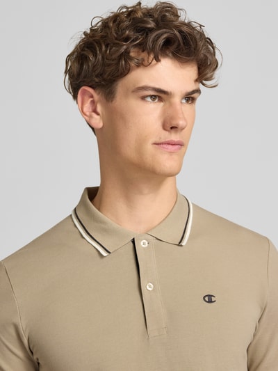 Männermodel trägt Slim Fit Poloshirt mit Label-Stitching von CHAMPION in Beige, Reine Baumwolle, Knopfleiste, Nahaufnahme Oberkörper. Rückenlänge bei Größe M: 73 cm.