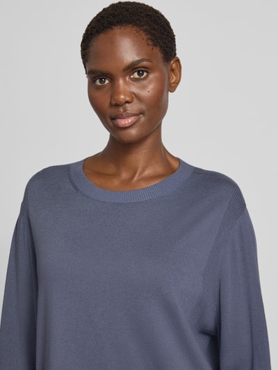 Frauenmodel trägt Longsleeve mit Woll-Anteil von Marc Cain in Blau, Rundhalsausschnitt, gerippte Partien, Nahaufnahme Oberkörper. Material-Mix aus Wolle und Viskose, lockere Passform, elastische Abschlüsse.