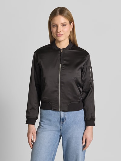 Frauenmodel trägt Regular Fit Bomberjacke mit Stehkragen Modell 'Beth' von khujo aus Elastischer-Material-Mix, Schwarz, Eingrifftaschen, Reißverschluss, Ganzkörperansicht von vorne. Rückenlänge 54 cm, Schulterbreite 46 cm, Brustweite 47 cm, Ärmellänge 58 cm, Größe S.