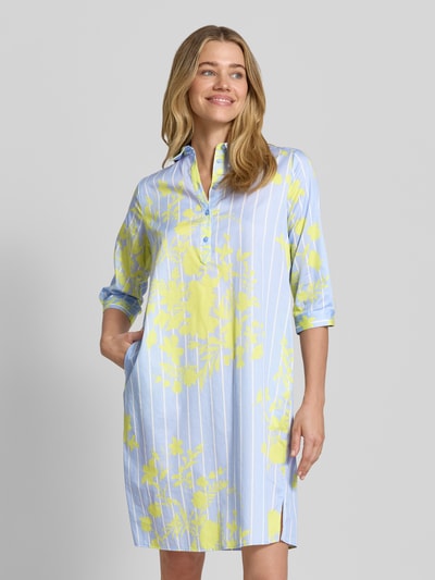 Frauenmodel trägt Knielanges Hemdblusenkleid mit kurzer Knopfleiste von Milano Italy aus Reine Baumwolle, Gerader-Schnitt, Knielänge, Hemdblusenkragen, 1/2-Arm, Rückenlänge bei Größe 36: 99 cm, Brustweite: 51 cm, Ärmellänge: 42 cm, mit blau-weißem Streifenmuster und gelbem Blumenprint, Ganzkörperansicht von vorne.