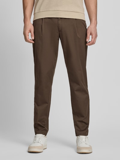 Męski model nosi chinosy z mieszanki bawełny i elastanu Brax Chino mit Eingrifftaschen Modell 'Tino', kolor brązowy, z wpuszczanymi kieszeniami, kantami, krój comfort fit, szerokość w rozmiarze 32/32: 42 cm, długość wewnętrzna nogawki: 77 cm, całkowity widok z przodu.