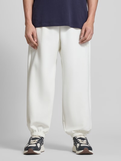 Männermodel trägt weiße Regular Fit Sweatpants mit Modal-Baumwoll-Anteil von adidas Sportswear, Sweat-Textur, Logo, Tunnelzug, Ganzkörperansicht von vorne