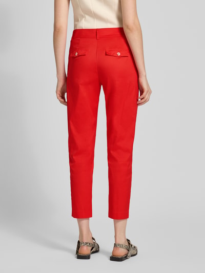 Frauenmodel trägt Slim Fit Stoffhose in verkürzter Passform von Christian Berg Woman aus elastischem Baumwoll-Mix in Rot, mit Eingrifftaschen, Gesäßtaschen, Knopf-Reißverschluss, Ganzkörperansicht Rückansicht.