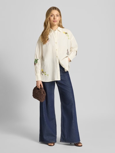 Frauenmodel trägt Relaxed Fit Bluse mit Stitchings von Scotch & Soda aus Baumwoll-Leinen-Mix, cremefarben, Hemdblusenkragen, Ganzkörperansicht von vorne.