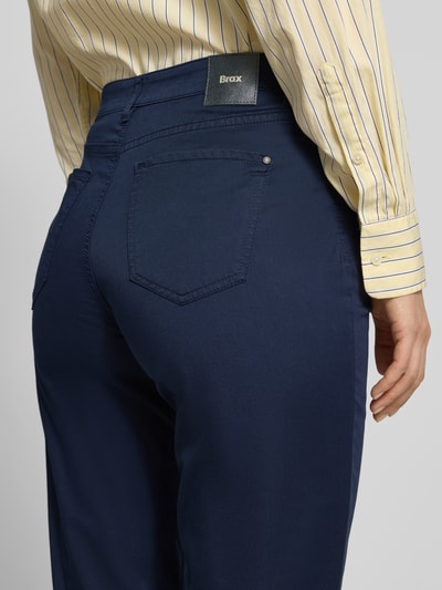 Kobiece modelka nosi spodnie z wpuszczanymi kieszeniami model 'Carola' od Brax z mieszanki bawełny i lyocellu, krój regular fit, szerokość w rozmiarze 36K: 39 cm, długość wewnętrzna nogawki 76 cm, kolor granatowy, tekstura gładka, detal tylnej kieszeni, ujęcie z tyłu detal.