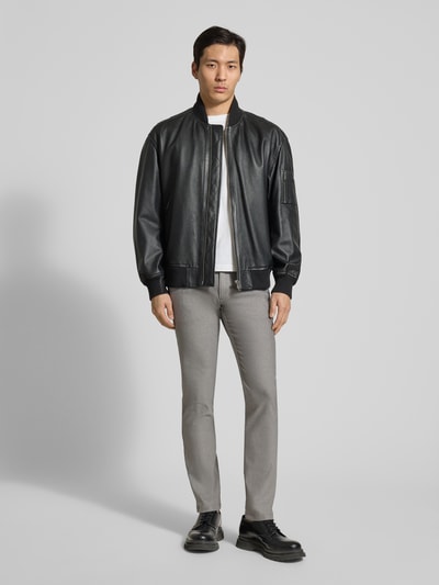 Męski model nosi Slim Fit Chino aus Baumwoll-Mix mit Leinen und Viskose-Anteil Modell 'Chino-Slim-2' od BOSS Orange, optyka denim, krój slim fit, mid waist, łatka z logo, zapięcie na guzik i kryty zamek, kieszenie z boku i tylne, materiał twill; pełen widok z przodu.