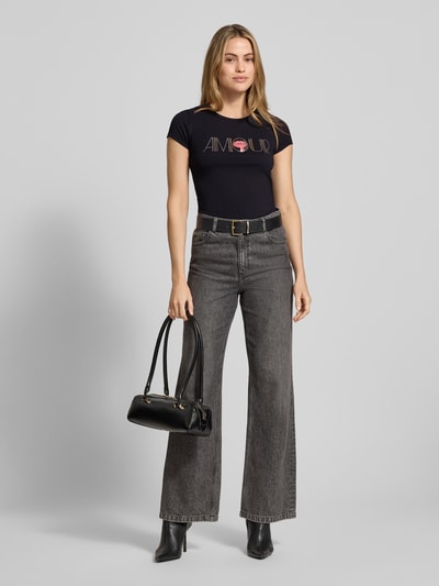 Vrouwenmodel draagt T-shirt met Ziersteinbesatz van Guess, zwart, mix van katoen en elastaan, slim fit, ronde hals, ruglengte 65 cm, geheelvooraanzicht.