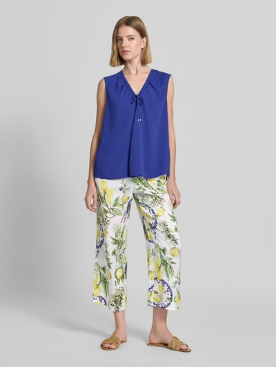Kobiece modelka nosi Straight Fit Stoffhose aus reiner Viskose mit Allover-Motiv-Print von Marc Cain, kolorowy nadruk z motywem na całej powierzchni, czysta wiskoza, krój straight fit, skrócony fason, częściowo elastyczny pas, szerokość w rozmiarze 36: 40 cm, długość wewnętrzna nogawki w rozmiarze 36: 64 cm, Ganzkörperansicht von vorne.