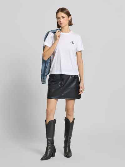 Kobiece modelka nosi Spódnica mini w linii A z materiału skóropodobnego z detalem z logo, wpuszczanymi kieszeniami marki Calvin Klein Jeans, szerokość w pasie 38 cm, całkowita długość 38 cm, cała sylwetka z przodu.