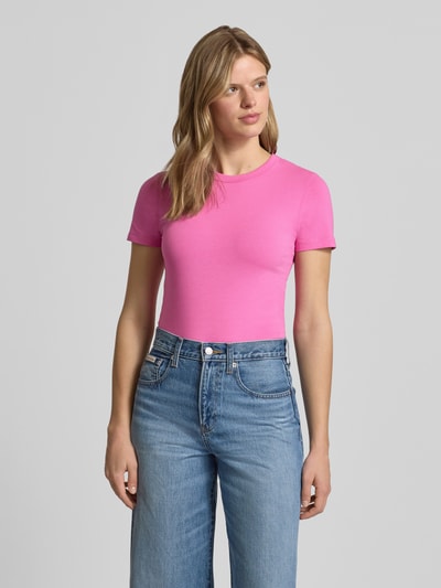Frauenmodel trägt T-Shirt mit Rundhalsausschnitt Modell 'GIGI' von JJXX in Pink, aus Baumwoll-Elasthan-Mix, Regular Fit, Nahaufnahme Oberkörper.