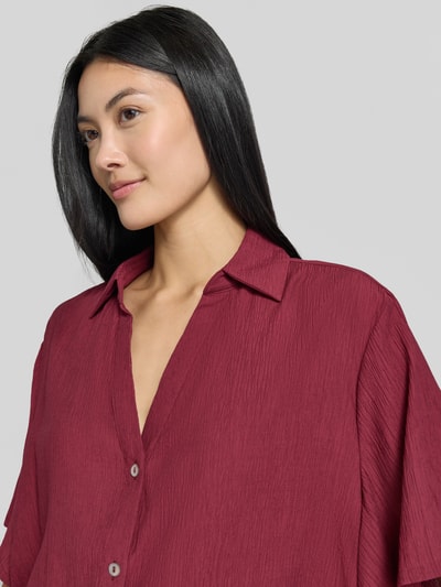 Kobiece model prezentuje Boxy Fit Kurzarmbluse aus Viskose-Mix od s.Oliver RED LABEL w kolorze bordowym, faktura lekko marszczona, zbliżenie na górną część ciała