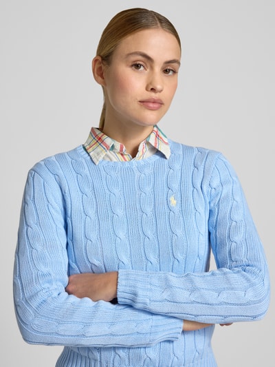 Frauenmodel trägt Regular Fit Strickpullover aus reiner Baumwolle Modell 'JULIANNA-LONG' von Polo Ralph Lauren, Optik: Unifarben, Zopfmuster, Kragenform: Crew Neck, Ärmelform: Langarm, Ärmelabschluss und Rumpfabschluss: Gerippt, Materialverarbeitung: Strick, Muster: Zopfmuster, Farbe hellblau, Nahaufnahme Oberkörper.