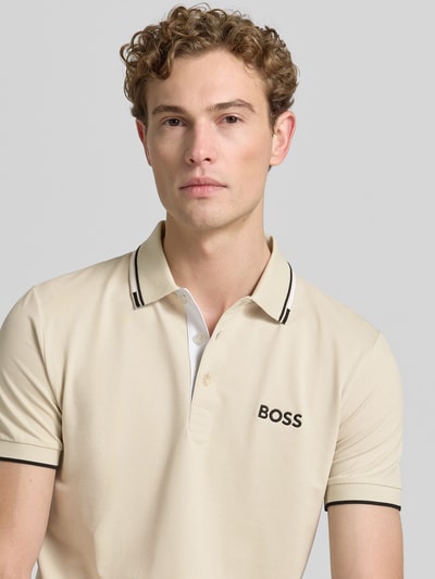 Mężczyzna nosi Regular Fit Poloshirt aus Baumwoll-Mix model 'PADDY PRO' von BOSS Green, beżowy z czarnymi detalami, zbliżenie na górną część ciała.