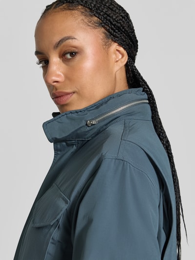 Frauenmodel trägt Windbreaker mit Pattentaschen von Kenzo, blaugraue Farbe, glatte Textur, Detailaufnahme Oberkörper, Damenmodell KI-modifiziertes Bild