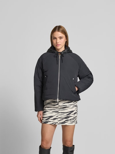 Kobiece model prezentuje bomberka z wypełnieniem puchem i pierzem od Moose Knuckles, elastyczna mieszanka materiałów, krój prosty, kaptur z tunelem, zamek błyskawiczny dwustronny, długość tyłu w rozmiarze S: 60 cm, szerokość w rozmiarze S: 60 cm, długość rękawów w rozmiarze S: 55 cm, przód, cała sylwetka.