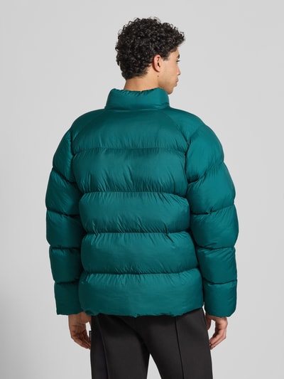 Männermodel trägt Steppjacke mit Label-Print von PUMA PERFORMANCE in Dunkelgrün, Unifarben, Baumwolle, gerader Schnitt, Ganzkörperansicht Rückansicht.
