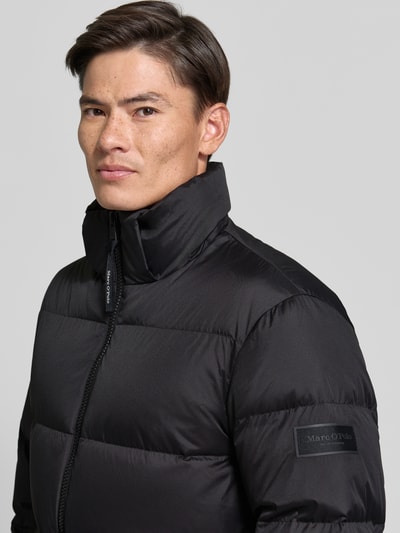 Männermodel trägt Regular Fit Daunenjacke mit Kapuzenkragen von Marc O'Polo, schwarz unifarben, wasserabweisend, Nahaufnahme Oberkörper.
