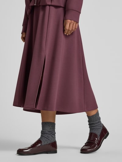Frauenmodel trägt Midirock mit elastischem Bund von Christian Berg Woman in dunklem Beerenton, lockere Passform, glatte Textur, Nahaufnahme Unterkörper, Damen Midirock von Christian Berg Woman, Elastischer Material-Mix mit Modal-Anteil, Midilänge, Bundweite bei Größe S: 80 cm.