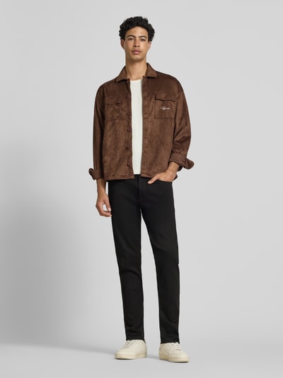 Männermodel trägt Slim Fit Jeans im 5-pocketmodel von G-Star Raw in zwart katoenmix met stretch, ganzkörperansicht von vorne. Context: heren slim fit jeans van G-Star Raw, katoenmix met stretch, slim fit, 5-pocketmodel, knoop- en ritssluiting, bandwijdte bij maat 32/32: 46 cm, binnenbeenlengte bij maat 32/32: 80 cm.