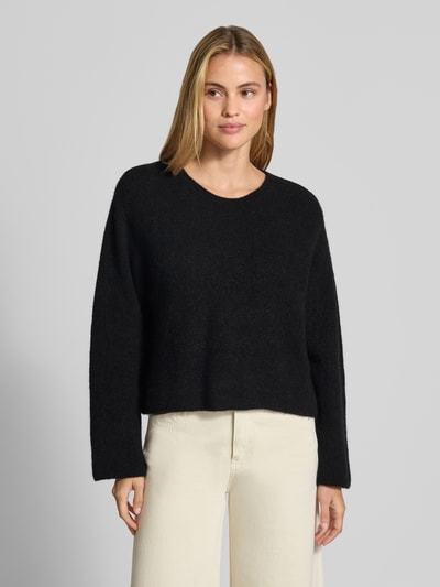 Frauenmodel trägt Strickpullover aus Alpaka-Leinen-Mix Modell 'VITOW' von American Vintage in Schwarz, lockere Passform, Nahaufnahme Oberkörper. Damenpullover mit Rundhalsausschnitt, Rückenlänge 53 cm, Ärmellänge 61 cm, Stretch-Anteil im Material.