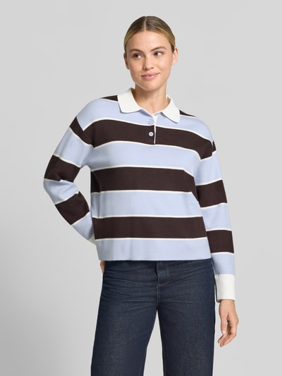 Frauenmodel trägt Regular Fit Poloshirt aus Viskose-Mix von MANGO, breite Streifen in Hellblau und Dunkelbraun, Polokragen, elastische Ärmelabschlüsse, langärmelig, Ganzkörperansicht von vorne.