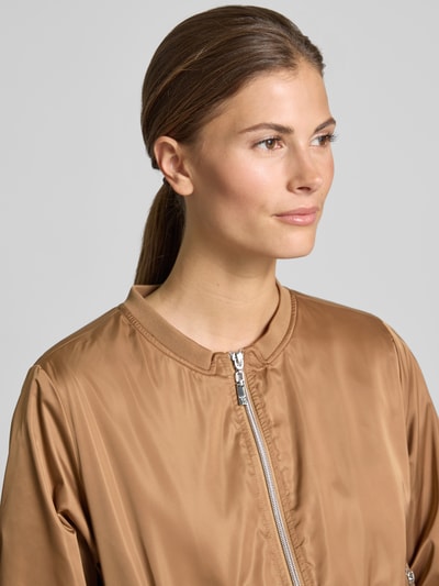 Frauenmodel trägt Jacke mit Rundhalsausschnitt und Reißverschlusstaschen von monari in Braun, Regular-Fit, Nahaufnahme Oberkörper. Rückenlänge bei Größe 36: 52 cm, Schulterbreite: 46 cm, Brustweite: 53 cm, Ärmellänge: 57 cm, glatte Textur.