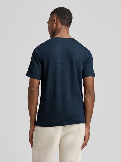 Mannelijk model draagt T-shirt uit mix van linnen en elastaan met ronde hals van OLYMP Level Five, regular fit, labeldetail, ruglengte bij maat M 69 cm, donkerblauw, textuur zichtbaar, geheellichaamsaanzicht achteraan.