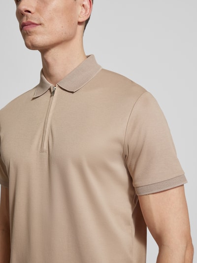 Männermodel trägt Regular Fit Poloshirt aus Bio-Baumwoll-Mix Modell 'FAVE' von SELECTED HOMME, beige, unifarben, Nahaufnahme Oberkörper.