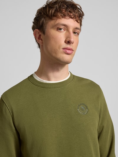 Männermodel trägt Regular Fit Pullover mit Logo-Stitching Modell 'Kane' von Blend in Olivgrün, Baumwoll-Mix, Nahaufnahme Oberkörper.