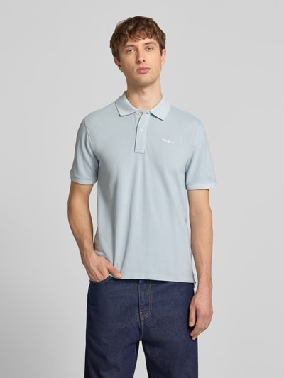 Männermodel trägt Regular Fit Poloshirt aus reiner Baumwolle Modell 'OSCAR' von Pepe Jeans in Optik: Unifarben, Label-Stitching-Applikation, Polokragen, V-Ausschnitt, Verschluss: kurze Knopfleiste, Ärmelform: Kurzarm, Ärmelabschluss: Gerippt, Rumpfabschluss: mit Seitenschlitzen, Materialverarbeitung: Piqué, Material: Reine Baumwolle, helle Farbe, Ganzkörperansicht von vorne.
