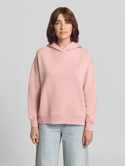 Frauenmodel trägt Oversized Hoodie aus Baumwolle von Closed in Rosa mit überschnittenen Schultern und Print, Ganzkörperansicht von vorne.