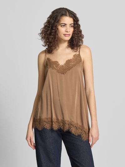 Frauenmodel trägt Relaxed Fit Top aus Viskose-Mix Modell 'Tami' von OH APRIL, braun mit Spitzenbesatz, asymmetrisch, Nahaufnahme Oberkörper.