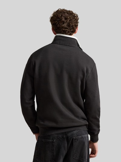 Männermodel trägt Relaxed Fit Troyer aus Baumwoll-Mix von Polo Ralph Lauren in Schwarz mit grauem Kragen, Ganzkörperansicht Rückansicht.