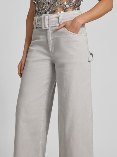 Frauenmodel trägt Wide Fit Jeans mit integriertem Gürtel von BAUM & PFERDGARTEN in hellem Grau, 5-Pocket-Design, Baumwoll-Mix, Nahaufnahme Oberkörper.