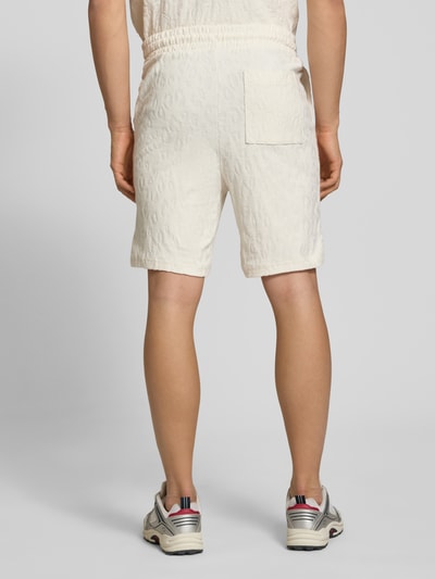 Männermodel trägt Regular Fit Shorts aus Frottee von HUGO in heller Frottee-Optik, mit Tunnelzug, Logo-Stitching, seitliche Eingrifftaschen, aufgesetzte Tasche hinten, Ganzkörperansicht Rückansicht.