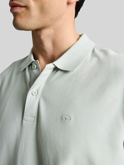 Männermodel trägt Regular Fit Poloshirt aus reiner Baumwolle von Tom Tailor, Optik: Unifarben, Logo-Stitching, Nahaufnahme Oberkörper.